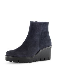 Bottines en suède bleu marine à talon compensé, avec une surface texturée, un bout arrondi et une semelle en caoutchouc proéminente avec un motif en zigzag.