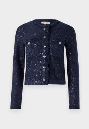 Laivastonsininen neuletakki, jossa on kimaltavia paljetteja, pyöreä kaula-aukko ja kaksi rintataskua. Varustettu nappikiinnityksellä, jossa on metalliset yksityiskohdat ja texturoitu materiaali.