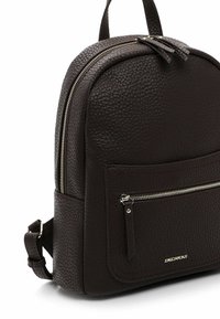 Dark brown textured leather backpack with front zip pocket, top handle, adjustable shoulder strap, and silver zipper details.