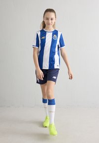 Ifjúsági focicsomag kék-fehér csíkos, címeres mezből, sötétkék rövidnadrágból, kék zokniból és élénksárga stoplis cipőből áll.