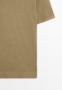 Brązowa bawełniana koszulka, krótki rękaw, okrągły dekolt, gładka tekstura i proste zakończenie. Bez wzorów ani dodatkowych detali.