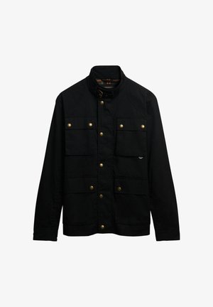 Schwarze Jacke aus strapazierfähigem Stoff, mit hohem Kragen, mehreren vorderen Taschen und goldfarbenen Druckknöpfen. Mit einer subtilen Mustertextur.