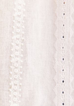 Hvidt stof med to lodrette broderede blonder; den ene med små blomster mønstre, den anden med bølgede kanter og små sorte prikker.