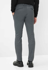 Pantaloni grigi realizzati in tessuto testurizzato, con vestibilità slim, tasche posteriori e abbinati a scarpe nere.