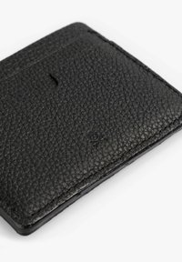 Billetera de cuero negra con superficie texturizada, que presenta un diseño minimalista y un sutil logo en relieve en la esquina inferior derecha.