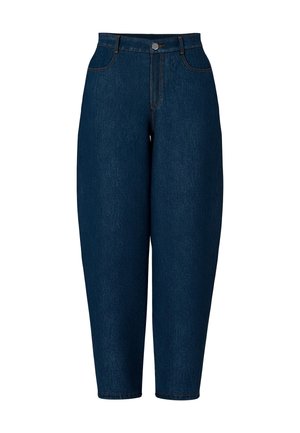 Kvinde iført sort læderjakke, hvid ribbet top, højttaljede viddeblå jeans og sorte ankelstøvler med hæl, stående med hænderne i lommerne.