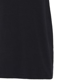 Ourlet de chemise en tissu noir uni avec coutures visibles sur fond blanc.