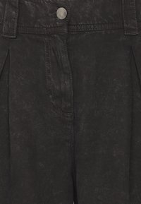 Zwarte denim broek met plooien, een metalen knoopsluiting en voorzakken. De stof heeft een gestructureerde afwerking met een vervaagd uiterlijk.