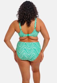 Twee-delige bikini met een groen-wit zigzagpatroon. De bovenkant heeft brede banden en een sluiting op de rug; de hoge taille onderkant biedt volledige bedekking.