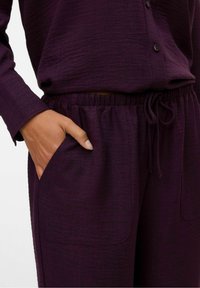 Fialový set domácího oblečení se strukturovanou tkaninou, košilí na knoflíky, elastickým pasem a stahovací šňůrkou, a kapsami po bocích.