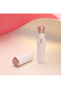 Elektrische trimmer in het wit met roségouden accenten; compact ontwerp met een ronde kop en afneembare kap. Glad oppervlak, draagbaar voor onderweg.