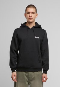 Felpa nera con cappuccio realizzata in misto cotone, caratterizzata da una tasca frontale e un logo ricamato. Vestibilità standard con polsini e orlo a coste.