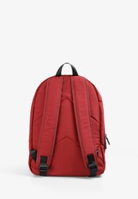 Mochila roja acolchada con correas negras, un asa superior y un patrón de diamante texturizado en la parte trasera. Cuenta con correas de hombro ajustables.