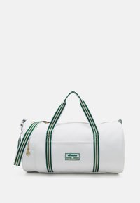 Borsa duffel bianca con manici a strisce verdi e bianche, dotata di una cerniera dorata, logo ricamato e forma cilindrica. Texture liscia.