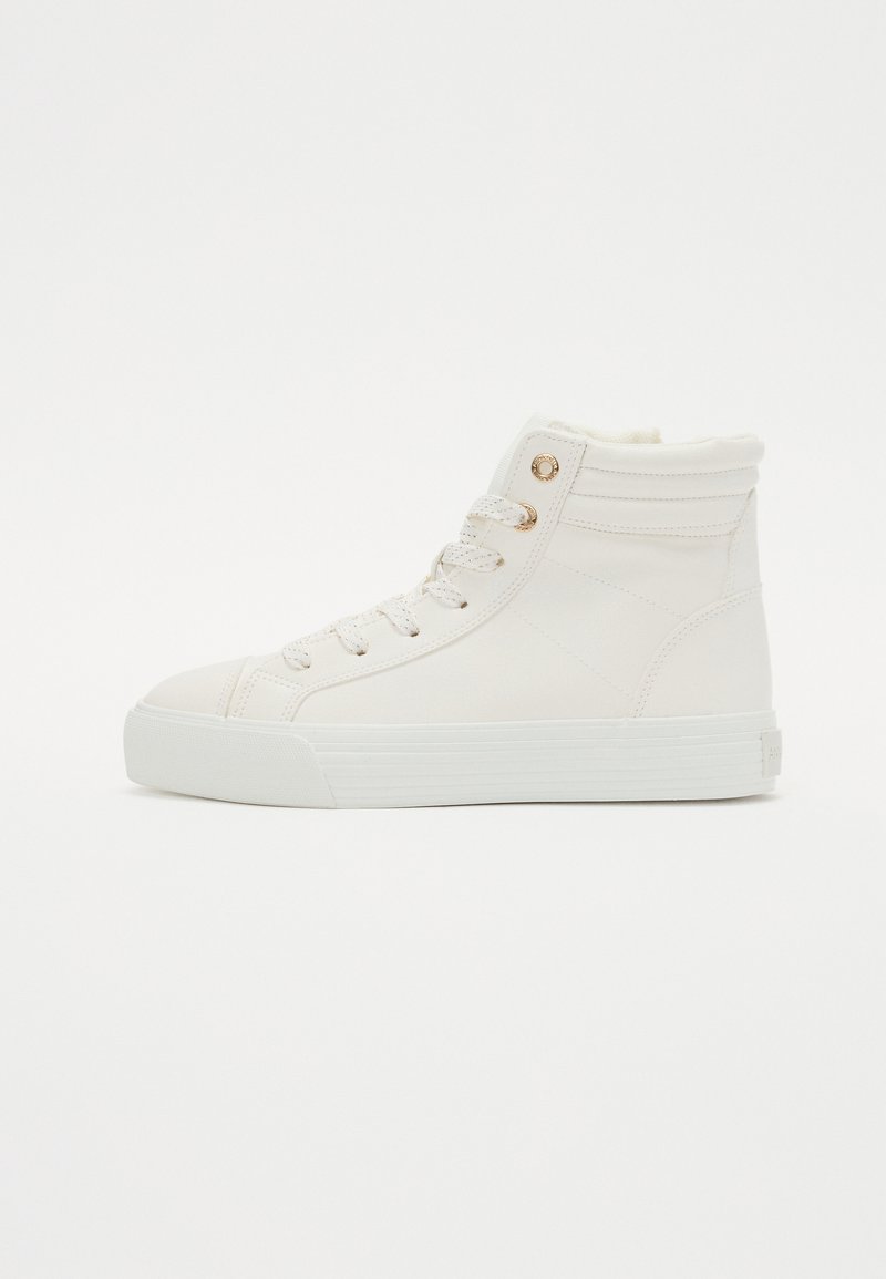 Basket high en matériau synthétique blanc, avec un dessus texturé, bout rond, lacets à l'avant et œillets dorés pour accent.