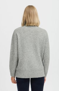 Suéter gris de punto con un corte holgado, textura acanalada, mangas largas y un escote alto. El dobladillo es recto, en contraste con pantalones oscuros.