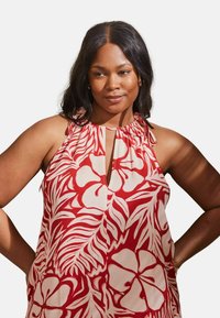 Röd och vit blommönstrad ärmlös topp med nyckelhålskrage och instoppade detaljer vid axlarna. Lätt och luftigt tyg.