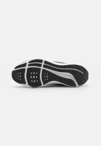 Suela de zapatilla deportiva blanca con goma negra texturizada y tracción con patrón. Presenta un diseño esculpido con surcos para agarre y flexibilidad.