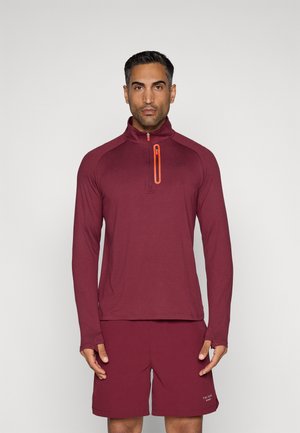 Maroon long-sleeve top with a quarter-zip collar and orange zipper detail, paired with matching shorts, made from lightweight, stretchy material.