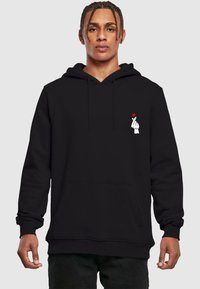 Black hoodie with a front pocket, featuring a white hand graphic with a small red heart. Material appears soft and textured.