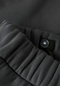 Donkergrijze elastische tailleband met verstelbare knoop en stoflusdetail op zachte jersey broek of short.