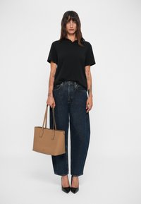 Polo shirt negru cu mânecă scurtă, blugi largi de culoare albastru închis cu talie înaltă, geantă tote bej și pantofi cu toc ascuțit negri.