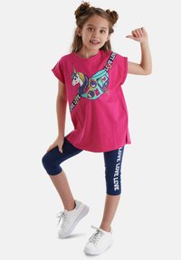 Lyserød bomulds T-shirt med korte ærmer og et enhjørningsprint, parret med marineblå leggings med "LOVE" tekst og hvide sneakers.