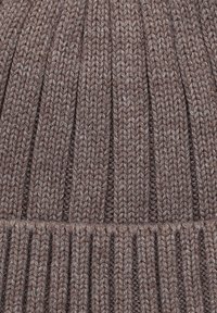 Dzianinowa czapka w stonowanym brązowym kolorze, z prążkowaną teksturą i poziomymi liniami. Materiał wydaje się miękki i ciepły.