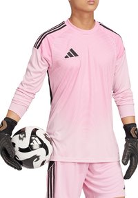 Maglia da portiere a maniche lunghe rosa con accenti neri, caratterizzata dal logo Adidas e da un design testurizzato; abbinata a guanti neri e a un pallone da calcio.