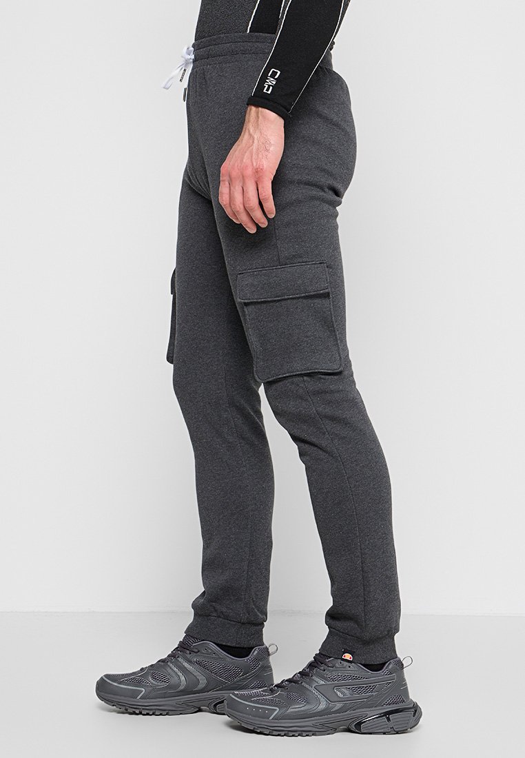 Ciemnoszare spodnie cargo z bocznymi kieszeniami, elastycznym pasem i sznurkiem. Noszone z szarymi butami sportowymi z siateczkowymi panelami.