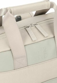 Borsa in tessuto grigio chiaro con texture, manici superiori doppi, base grigia liscia, logo inciso e tiranti della zip a contrasto.