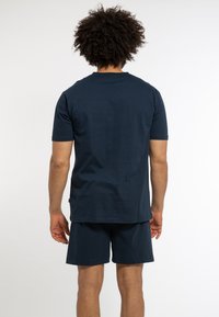 Navyblaues Baumwoll-T-Shirt mit kurzen Ärmeln und Rückennahtdetails, kombiniert mit passenden Shorts, die einen lässigen Schnitt haben.