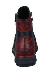 Schwarze und rote Knöchelstiefel aus strukturiertem Leder, mit doppelten seitlichen Reißverschlüssen und dicker schwarzer Sohle, von hinten gezeigt.