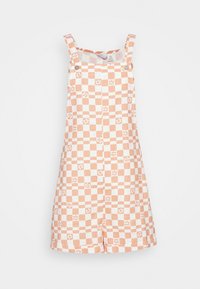 Combinaison salopette à carreaux orange et blanc. Réalisée en tissu léger avec bretelles ajustables et fermeture à boutons-pression.