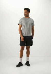 Gray short-sleeve t-shirt paired with black athletic shorts. The look is completed with black sneakers and white crew socks.