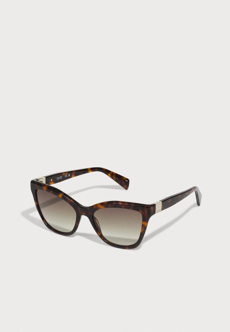 Des lunettes de soleil en forme de chat avec un motif écaille de tortue, des verres dégradés marron foncé et des accents métalliques sur les branches. Fini en plastique lisse.