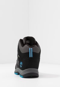 Zwarte en grijze wandelschoen met een gestructureerde suede en mesh bovenkant, voorzien van blauwe accenten, een gevoerde kraag en een duurzame rubberen zool.