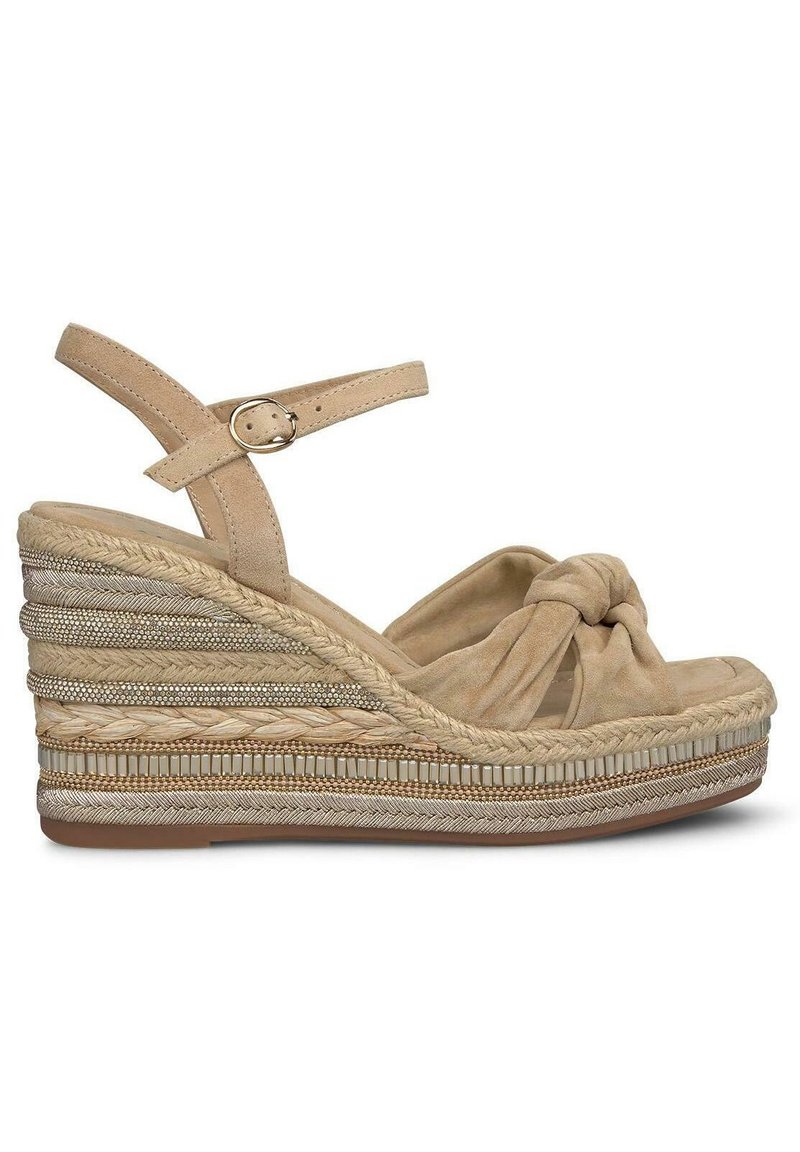Sandales compensées beiges avec un devant noué, des sangles en cuir et des détails en espadrille tressée. Présente une semelle texturée et des accents métalliques.