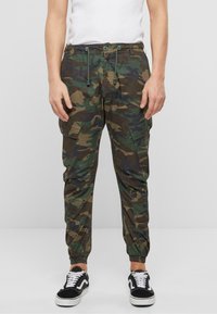 Pantalones jogger de camuflaje en tonos verdes y marrones, con cintura elástica, cordón ajustable, bolsillos tipo cargo y puños ajustados.