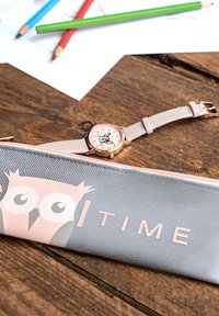 Grau Bleistiftetui mit Eulenmotiv und pinken Akzenten, kombiniert mit einer runden, roségoldenen Uhr mit einem weißen Zifferblatt und einem hellpinkfarbenen Armband.