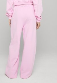 Pinke Sweatpants mit weitem Bein und elastischem Bund. Hergestellt aus weichem, strukturiertem Baumwollstoff. Mit glatten Säumen ohne sichtbare Muster.