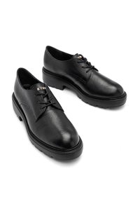 Paire de chaussures en cuir noir à lacets avec semelles en caoutchouc épaisses, bouts arrondis et finition texturée subtile sur fond blanc.