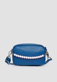 Blauwe leren crossbody-tas met een gestructureerde afwerking, voorzien van een roze kraalaccent aan de voorkant, een verstelbare schouderriem en zilverkleurige hardware.