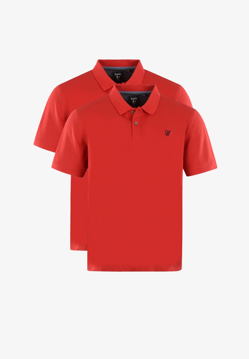 Två röda polo-skjortor i bomull, med klassisk krage, korta ärmar och ett litet emblem på bröstet. Lättviktsmaterial.
