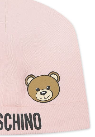 Berretto lavorato a maglia rosa con grafica di un orso marrone e testo nero "MOSCHINO" sul bordo. Texture liscia e forma arrotondata.