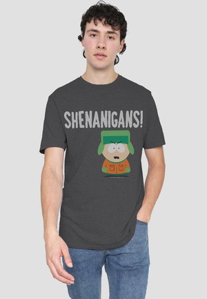 Dunkelgraues T-Shirt mit Rundhalsausschnitt, das den Text "SHENANIGANS!" und eine Cartoonfigur mit grünem Hut, orangefarbener Jacke und grünen Handschuhen zeigt.