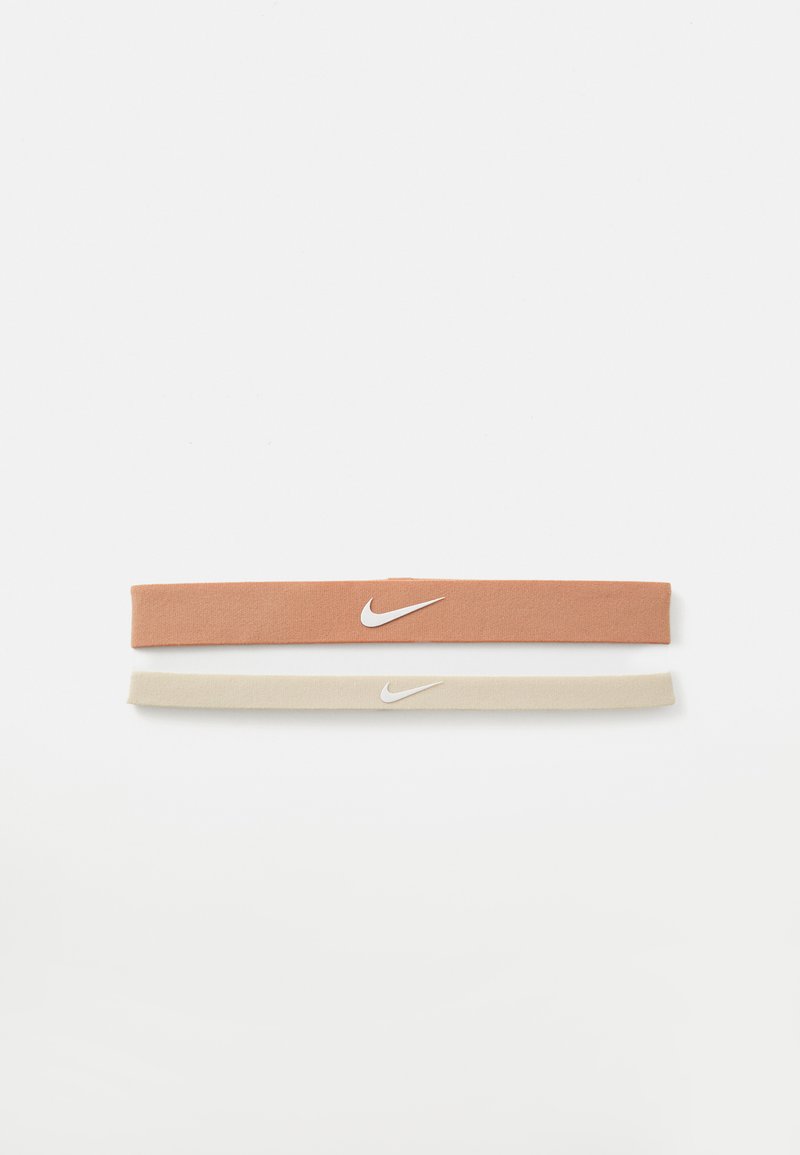 Two fabric hairbands: one in terracotta with a white Nike logo, the other in beige. Both feature a smooth texture and flexible design.
