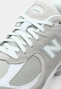Light gray running shoe with suede and mesh materials, featuring white accents, textured laces, and a prominent "N" logo on the side.
