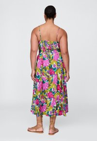 Vestido maxi floral com corpete franzido, apresentando grandes padrões tropicais em rosa e verde. Alças finas e silhueta fluida.