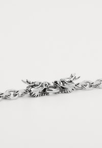 Silver chain bracelet featuring intricately designed dragon heads as clasps, with polished texture and detailed accents on the creatures.